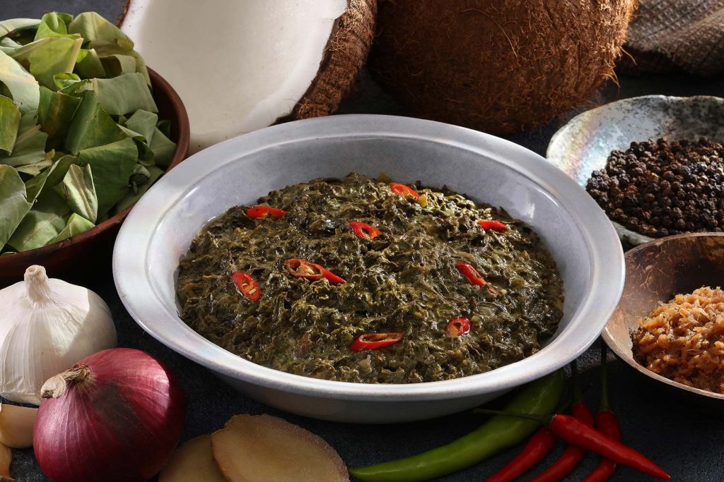 Laing, a dish with coconut milk and gabi leaves, topped with chopped chili