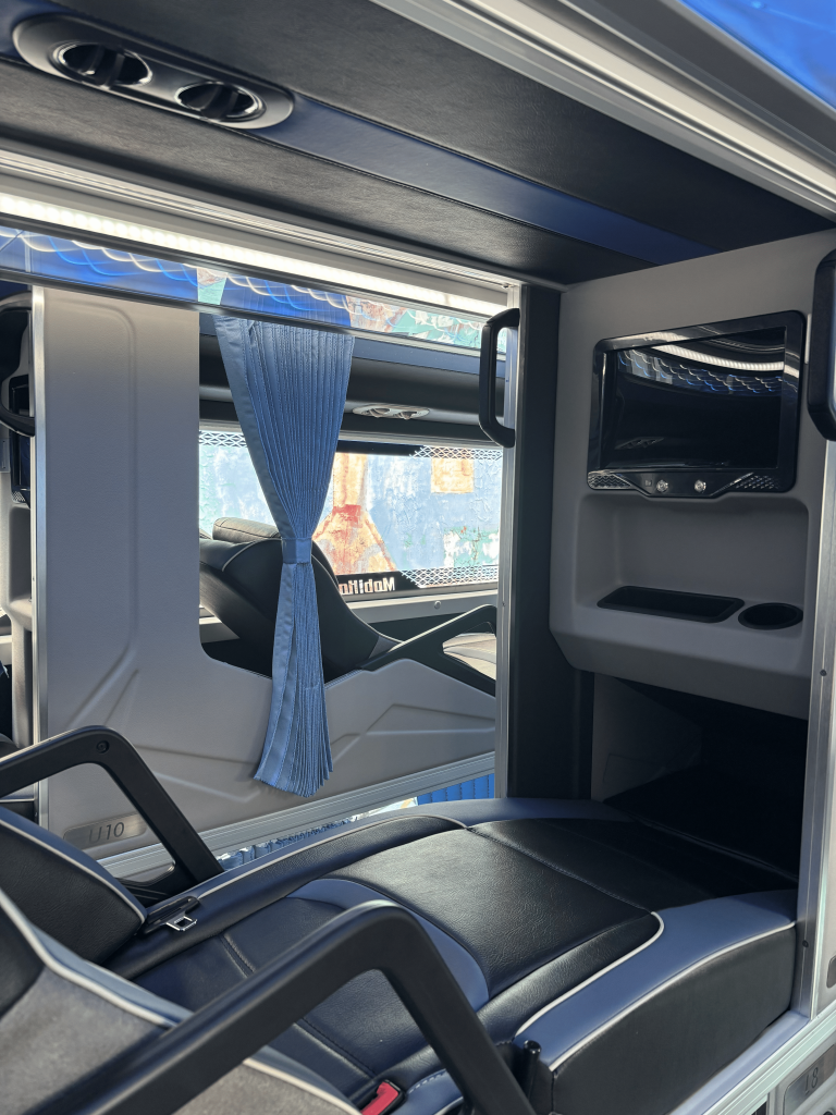 Upper bunk bed on the ALPS’ Sleeper Master Class bus, featuring the entertainment screen and trays