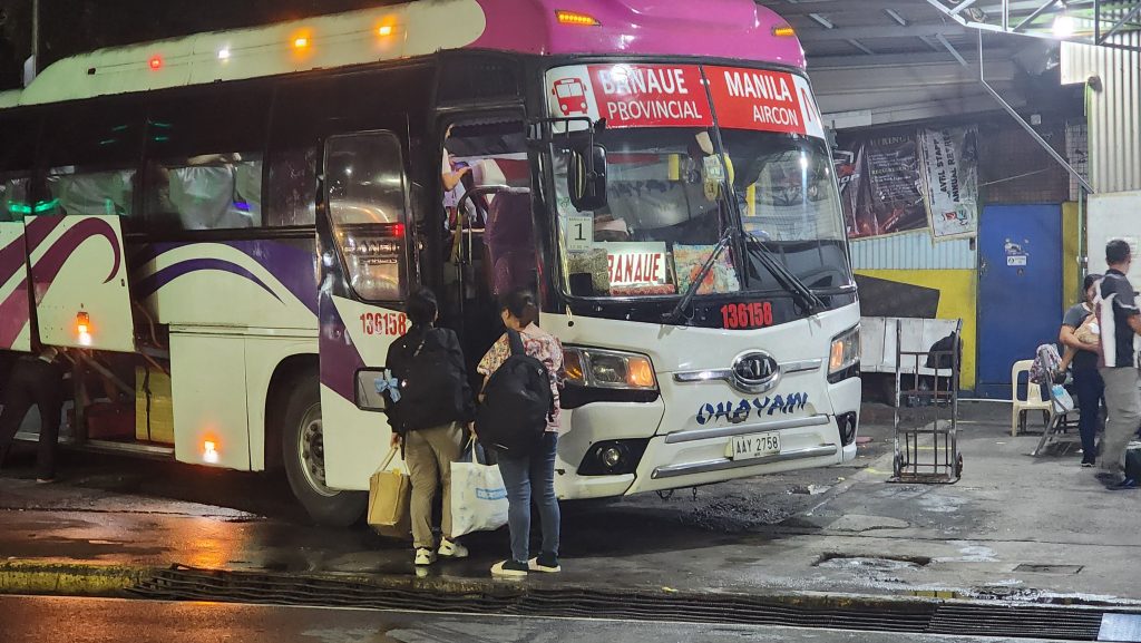 Passengers are boarding on a bus at night.